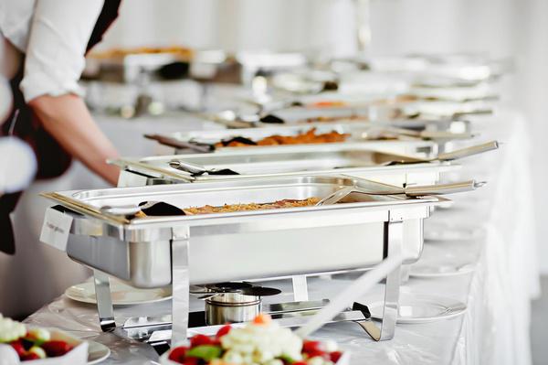 A professional chef prepares corporate event catering for a buffet.
